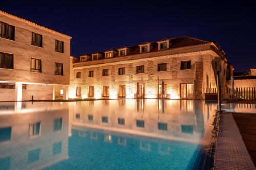 a swimming pool in front of two buildings at night at Castilla Termal Olmedo in Olmedo