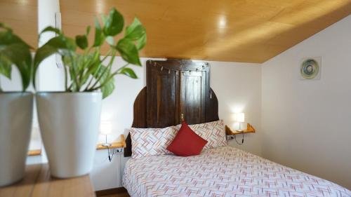 ベッルーノにあるLa Pecora Nera Bed & Breakfast Bellunoの木製ヘッドボードと植物を用いたベッド1台が備わるベッドルーム1室が備わります。