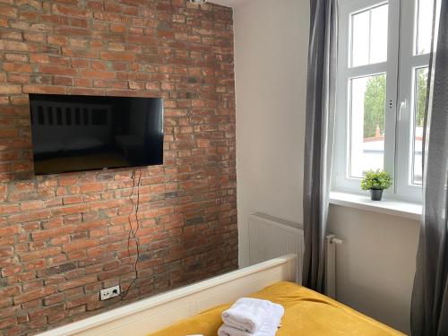 een slaapkamer met een bakstenen muur en een flatscreen-tv bij Dekerta 8-3 in Toruń