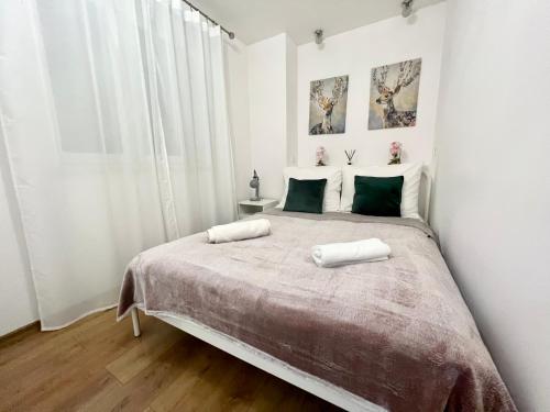 a white bedroom with a large bed with two white pillows at Melody Apartment in Krakow