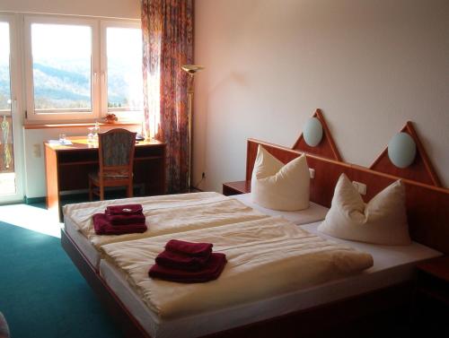 een slaapkamer met een bed met rode handdoeken erop bij Hotel und Gasthaus Rammelburg-Blick in Friesdorf