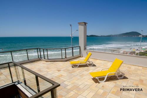 - deux chaises jaunes assises sur une terrasse près de la plage dans l'établissement Residencial Primavera, à Bombinhas