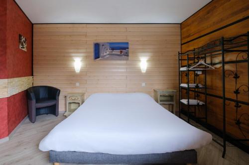 a bedroom with a large white bed and a chair at Eqynox Hotel in Vitry-le-François