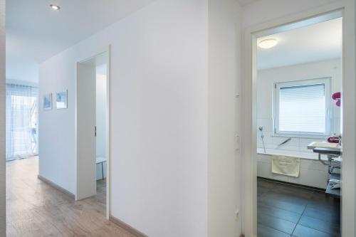einen weißen Flur mit Spiegel und ein Badezimmer in der Unterkunft Star - Vogelhaus in Friedrichshafen