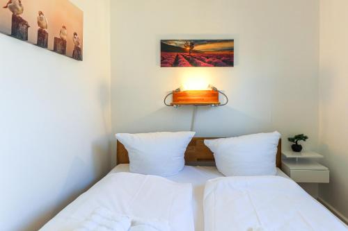 sypialnia z 2 łóżkami i lampką na ścianie w obiekcie Appartement Weststrand w mieście Westerland