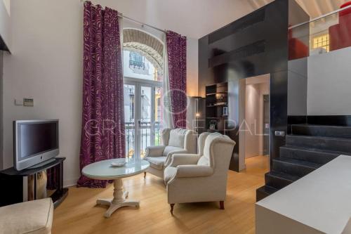 een woonkamer met stoelen, een tv en een raam bij FULL HOUSE NEAR CATHEDRAL AND REAL MAESTRANZA by Antonia Diaz street in Sevilla