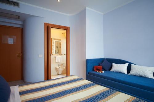 a room with a blue couch and a bed at Hotel Sirio in Lido di Camaiore