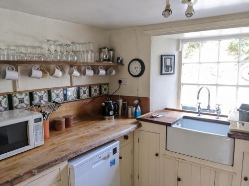 a kitchen with a sink and a microwave at Millers Cottage, Broughton - family & pet friendly in Broughton in Furness