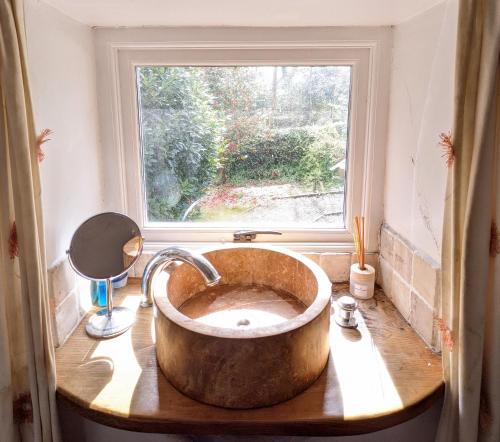 a bathroom with a large copper sink in front of a window at Millers Cottage, Broughton - family & pet friendly in Broughton in Furness