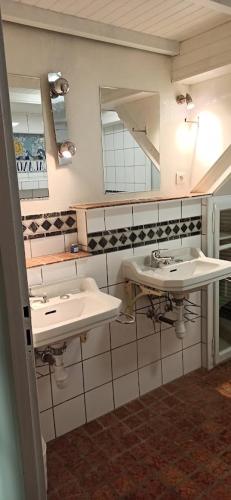 une salle de bain avec deux lavabos et deux miroirs dans l'établissement Les Falaises, à Yvoire