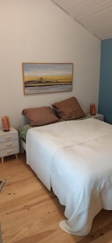une chambre avec un lit blanc et un tableau au mur dans l'établissement Les Falaises, à Yvoire