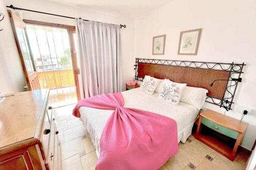 a bedroom with a bed with a pink blanket on it at Vera Mar 8A Primera linea con Piscina y Parking in Arona