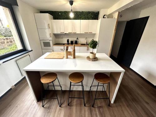 une cuisine avec un îlot blanc et deux tabourets dans l'établissement Le Puy en Velay - Appartement grand confort, au Puy-en-Velay