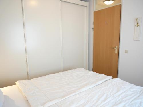 a white bed in a room with a closet at Badhotel Appartementen Callantsoog in Callantsoog
