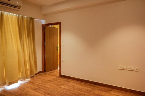 een lege kamer met een deur en een geel gordijn bij GRAND ONE TOWER in Chennai