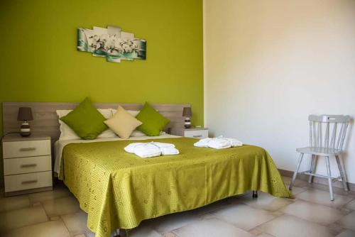 a bedroom with a bed with green walls and a chair at Blu Mare Lampedusa Bed And Breakfast in Lampedusa