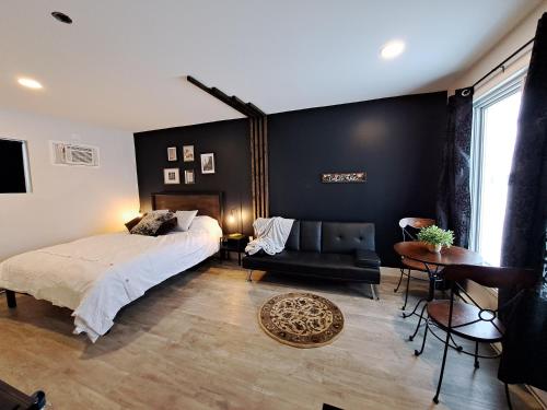 1 dormitorio con 1 cama, 1 silla y 1 mesa en Habitations Zenith en Sainte-Anne-de-Beaupré