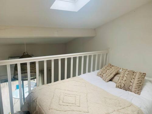 een slaapkamer met een wit bed met kussens erop bij La maison du Clos in Valras-Plage