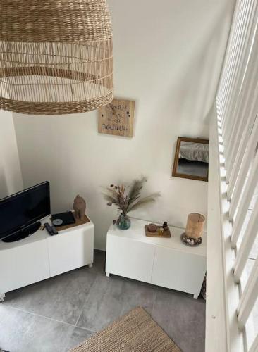 a living room with two white tables and a television at La maison du Clos in Valras-Plage