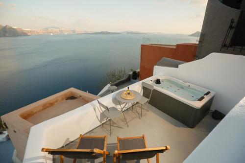 balcón con bañera de hidromasaje, mesa y sillas en Dream Cave Oia maisonette for 4 persons by MPS, en Oia