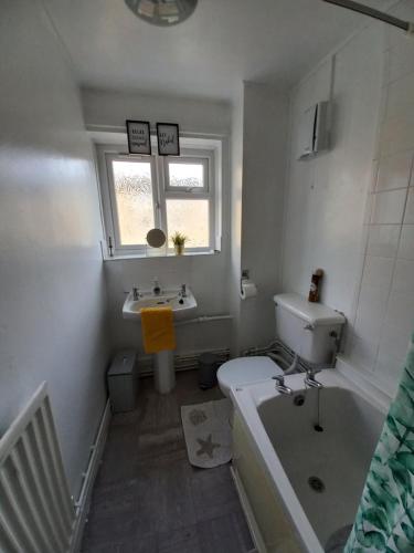 a bathroom with a tub and a toilet and a sink at Derby City Apartment with free parking in Derby