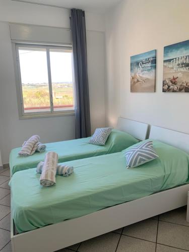 two twin beds in a room with a window at LoVi apartments Porto Palo in Porto Palo