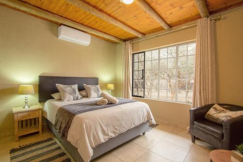 - une chambre avec un lit, une fenêtre et une chaise dans l'établissement Kudus Crest Bush Retreat, à Marloth Park