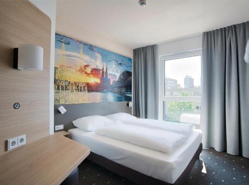 a hotel room with a bed and a window at B&B Hotel Köln-City in Cologne