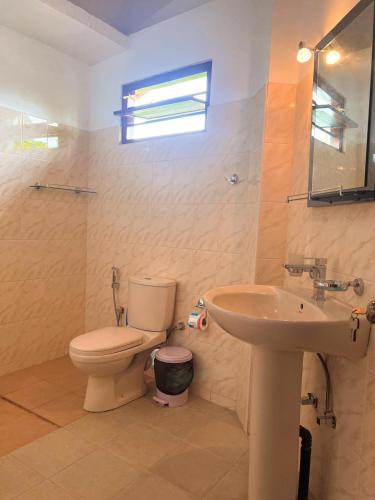 a bathroom with a toilet and a sink at Hummus Hostel Hikkaduwa in Hikkaduwa