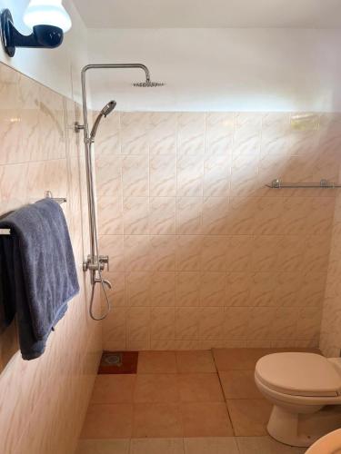 a bathroom with a shower with a toilet and a blue towel at Hummus Hostel Hikkaduwa in Hikkaduwa