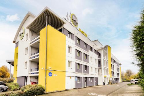 un immeuble d'appartements jaune et blanc dans l'établissement B&B HOTEL Köln-Frechen, à Frechen