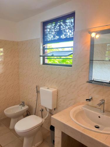 a bathroom with a toilet and a sink and a window at Hummus Hostel Hikkaduwa in Hikkaduwa