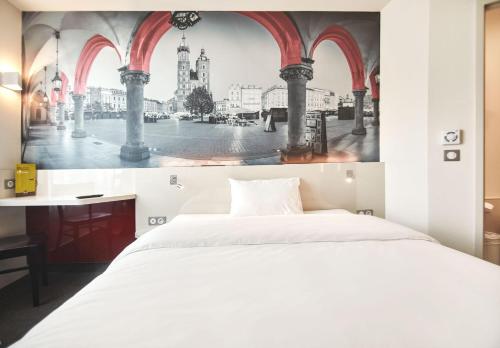 a bedroom with a white bed and a painting on the wall at B&B HOTEL Krakow Centrum in Kraków