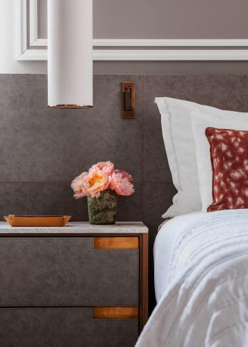 a bed with a table with a vase of flowers on it at One&Only Portonovi in Herceg-Novi