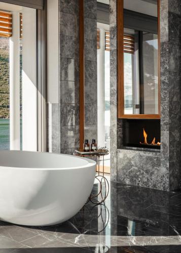 a bathroom with a tub and a fireplace at One&Only Portonovi in Herceg-Novi