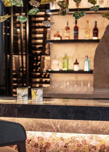 a bar with glasses on a counter with wine bottles at One&Only Portonovi in Herceg-Novi