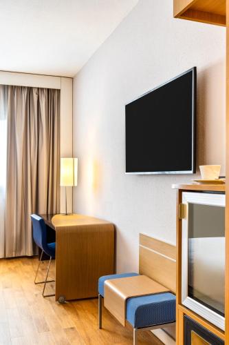 a hotel room with a flat screen tv on the wall at Novotel Caserta Sud in Caserta