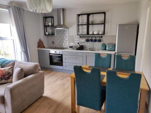 a kitchen with a table and blue chairs in a room at Apartments at Ballinsheen House & Gardens in Lisdoonvarna
