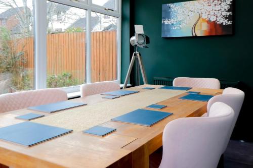 a conference room with a wooden table with white chairs at Hughes contemporary home in Barnstaple by StayStay com in Barnstaple