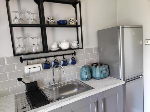 a kitchen with a sink and a refrigerator at Apartments at Ballinsheen House & Gardens in Lisdoonvarna