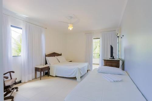 グアラジュバにあるGB19 Casa 7 Quartos a 50m da Praia - Guarajubaのベッドと机のある白い寝室