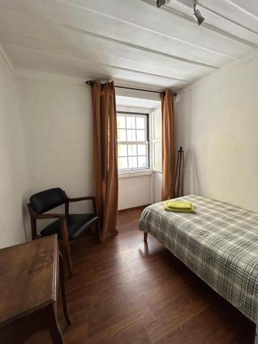 een slaapkamer met een bed, een stoel en een raam bij Bairro Alto Flat in Lissabon