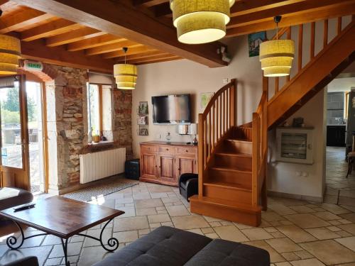 a living room with a staircase and a table at Domaine du Cuiset - Gite du Four a Pain in Saint-André-sur-Vieux-Jonc