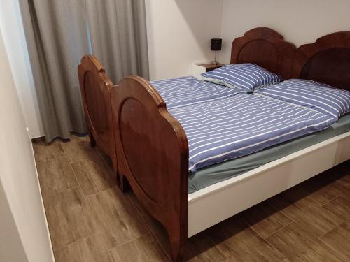 Cette chambre comprend un lit avec des têtes de lit en bois et du parquet. dans l'établissement Penzion Litohlavy 17 - Na samotě u lesa, à Králŭv Dvŭr