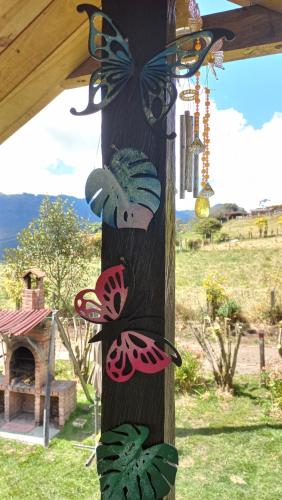 a wooden pole with butterflies painted on it at Espectacular cabaña campestre con granja in Zipaquirá