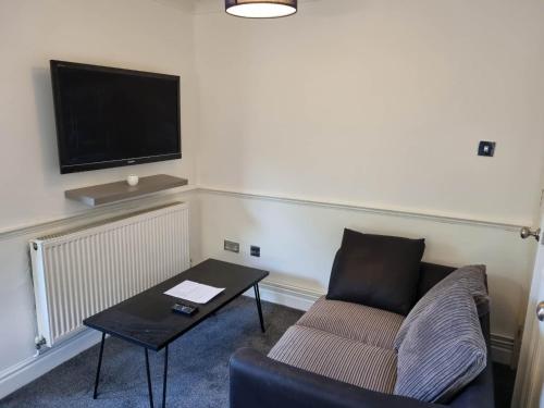 a living room with a couch and a table and a tv at Lovely City Studio near Station. Off Road Parking. in Norwich