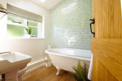 a bathroom with a bath tub and a sink at New Lane Cottage in Worstead