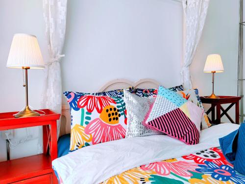 a bed with colorful pillows on it with two lamps at มารินอส บีชเฮ้าส์ Marinos Beach house in Si Racha