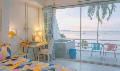 1 dormitorio con balcón con vistas al océano en มารินอส บีชเฮ้าส์ Marinos Beach house en Si Racha