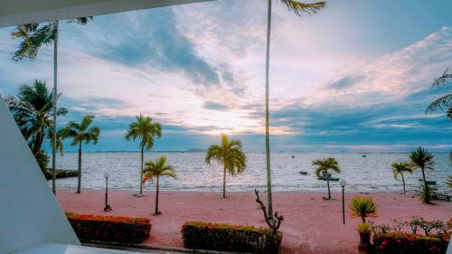 a view of a beach with palm trees and the ocean at มารินอส บีชเฮ้าส์ Marinos Beach house in Si Racha